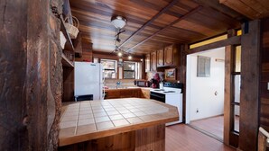 A rustic kitchen with wooden cabinets, a tiled countertop, and a ceiling fan. - Pet Friendly Rustic Cabin on the Animas River -  6 Min. to Downtown Durango (Durango)