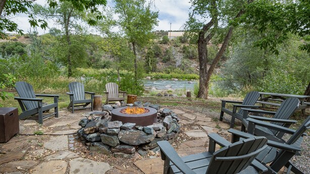 An outdoor seating area with Adirondack chairs and a stone fire pit. - Pet Friendly Rustic Cabin on the Animas River -  6 Min. to Downtown Durango (Durango)
