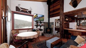 A cozy living room with a fireplace, a dining area, and a kitchen. - Pet Friendly Rustic Cabin on the Animas River -  6 Min. to Downtown Durango (Durango)