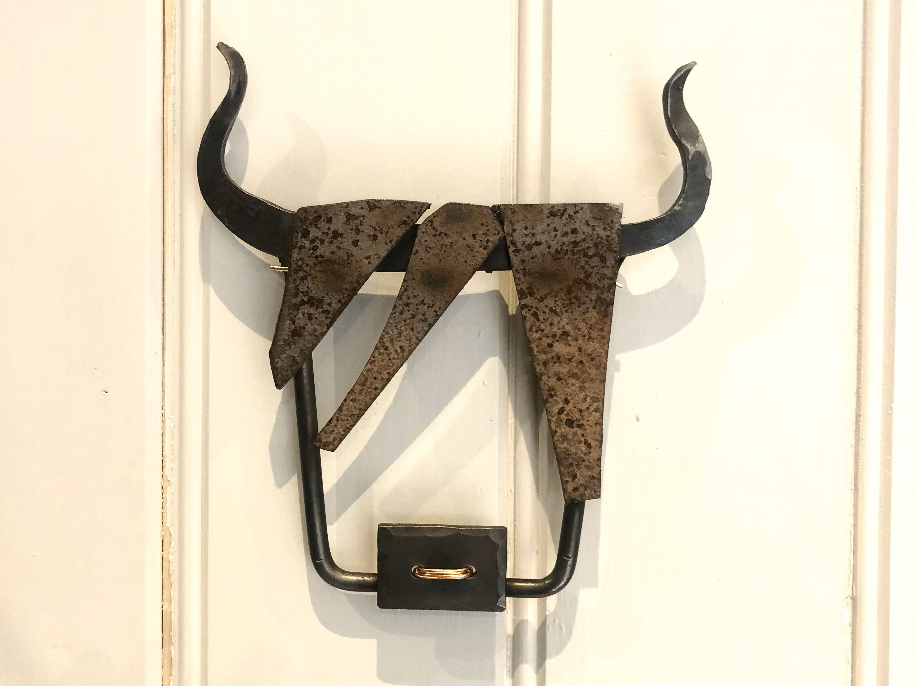 A metal object with a curved top and a rectangular base, mounted on a wall.