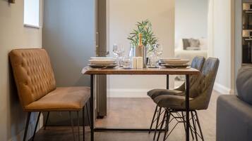 Comedor con mesa de madera, dos sillas, una planta en maceta y una botella de champán.