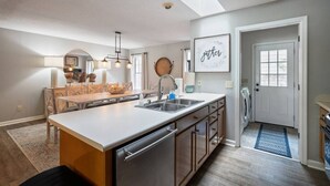 A modern kitchen with a central island, built-in appliances, and a dining area with a round table and chairs.