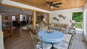A spacious living area with a round blue table, two sofas, and a ceiling fan.
