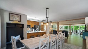 A spacious kitchen with wooden cabinets, a dining area with a large table and chairs, and a view of the outdoors through large windows.