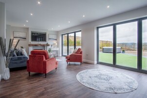 Amplia sala de estar con chimenea, ventanas grandes y vistas al exterior.