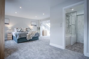 Een slaapkamer met een bed, nachtkastjes, een dressoir en een inloopkast.