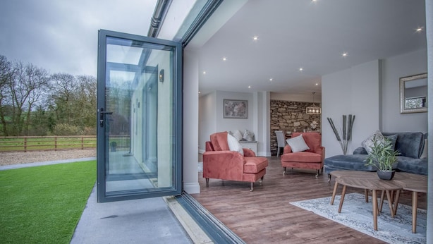 A modern living room with two sofas, a coffee table, and a stone wall. - Kiln Park Farmhouse - 4 Bedroom Cottage - Narberth (Narberth)