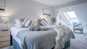 A modern bedroom with a large bed, a nightstand, a lamp, and a view of the sky through a skylight. - Kiln Park Farmhouse - 4 Bedroom Cottage - Narberth (Narberth)
