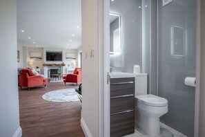 Een moderne badkamer met douche, toilet en wastafel.