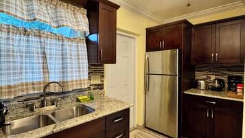 A kitchen with dark wood cabinets, a stainless steel refrigerator, and a granite countertop.