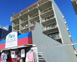 A multi-story building with a sign reading 'Tre's PLACE' and a clothing store at the ground level. - OC MD Direct Oceanfront Efficiency with pool parking gym White Marlin Open Week (Ocean City)