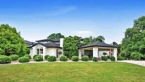 A two-story house with a covered patio, surrounded by well-maintained lawns and trees. - Sarovar Holidays (Traralgon)