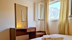 Une chambre à coucher avec un lit, une table de chevet avec une lampe, un miroir et une fenêtre avec des rideaux.