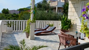 Un balcon avec deux fauteuils, une table et des plantes en pot.