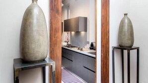 A modern kitchen with dark cabinetry, a central island, and two large vases on side tables.