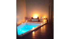 A small, rectangular pool with a wooden deck and a warm light source in the background.