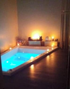 Ein kleiner, rechteckiger Pool mit einer Holzterrasse und einer warmen Lichtquelle im Hintergrund.