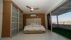 A bedroom with a bed, a ceiling fan, a sliding glass door, and a view of the outdoors. - Villa Yael eilat (Eilat)