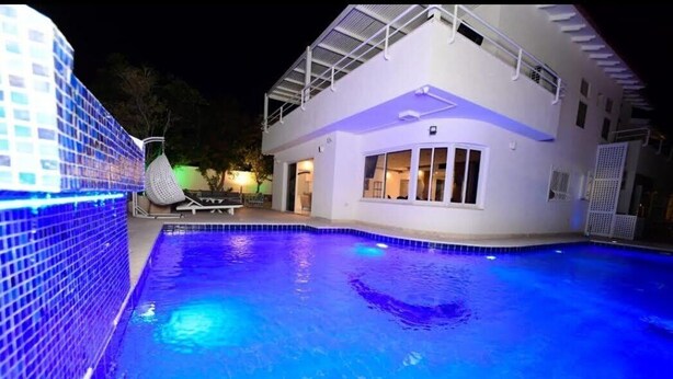 A swimming pool adjacent to a modern house with a covered patio area. - Villa Yael eilat (Eilat)