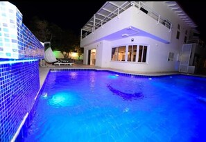 A swimming pool adjacent to a modern house with a covered patio area. - Villa Yael eilat (Eilat)