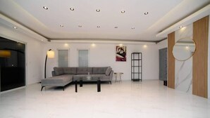 A modern living room with a sectional sofa, a coffee table, and a floor lamp. - Villa Yael eilat (Eilat)
