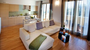 A modern living room with a white sofa, a dining table with chairs, and a kitchen in the background.