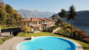 A large house with a swimming pool, surrounded by mountains and trees.