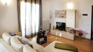 A modern living room with a sofa set, a TV, a small coffee table, and a decorative vase.