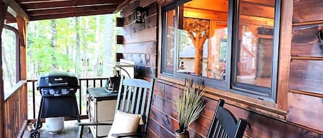 Eine Holzterrasse mit Grill, Stühlen und einem Tisch.