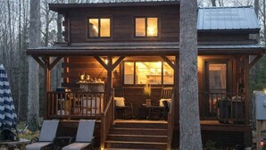 Eine Hütte mit Veranda, Sitzgelegenheit im Freien und einer sichtbaren Küchenzeile.