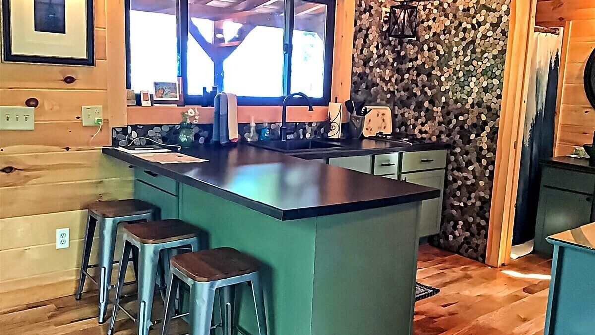 Une cuisine dotée d’un îlot central, de tabourets de bar, d’une fenêtre offrant une belle vue et de murs en bois.