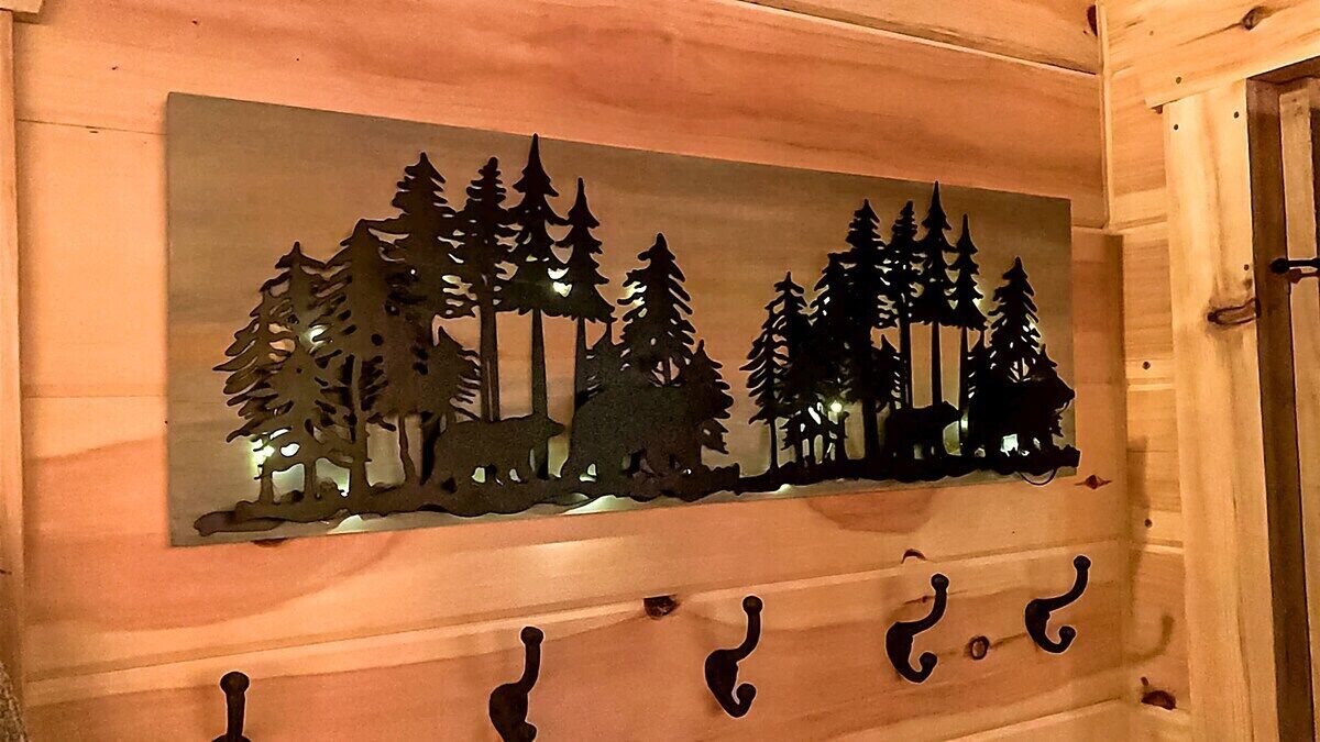 Un mur orné d’une silhouette d’arbres et d’un ours, et une porte en bois avec une poignée.