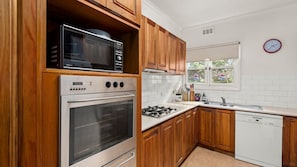 A kitchen with wooden cabinets, a microwave, an oven, a gas stove, and a dishwasher.
