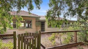 A two-story house with a tiled roof, a porch, and a wooden fence.