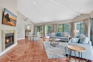 A spacious living area with a fireplace, a sofa, a dining table, and a kitchen in the background. - Subtropical Oasis -Naples, Fl Retreat (Naples)