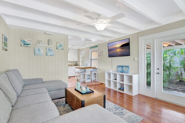 A modern living room with a grey sectional sofa, a wooden coffee table, and a TV mounted on the wall.