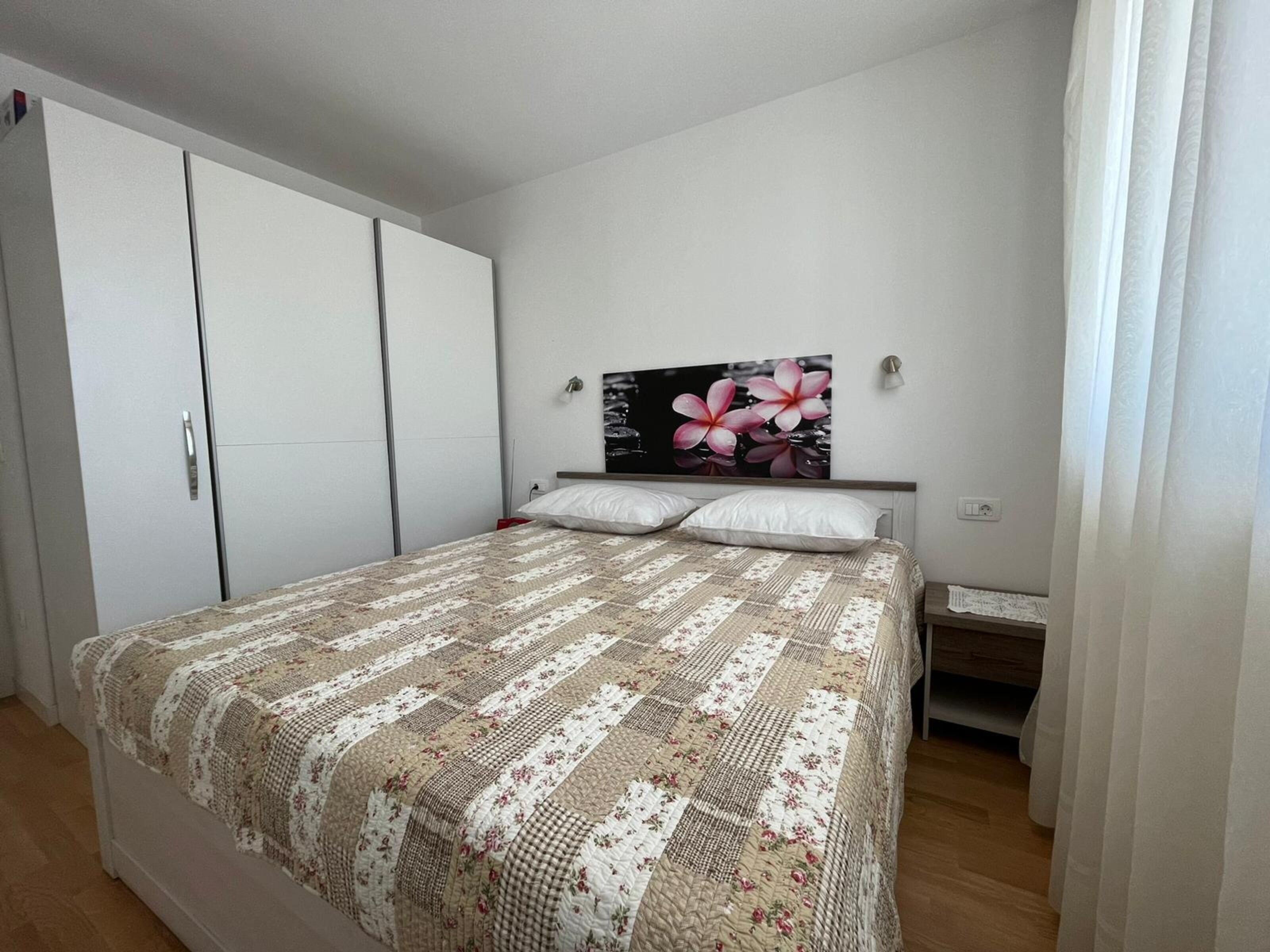 Ein Schlafzimmer mit Bett, Kleiderschrank, Nachttisch und einem Wandbild.