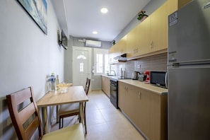 A compact kitchen with wooden cabinets, a stainless steel refrigerator, a microwave, and a kettle.
