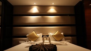 A hotel room with a neatly made bed, two golden pillows, and a swan-shaped towel arrangement. - THE LATITUDE LUXURY  (Haridwar)