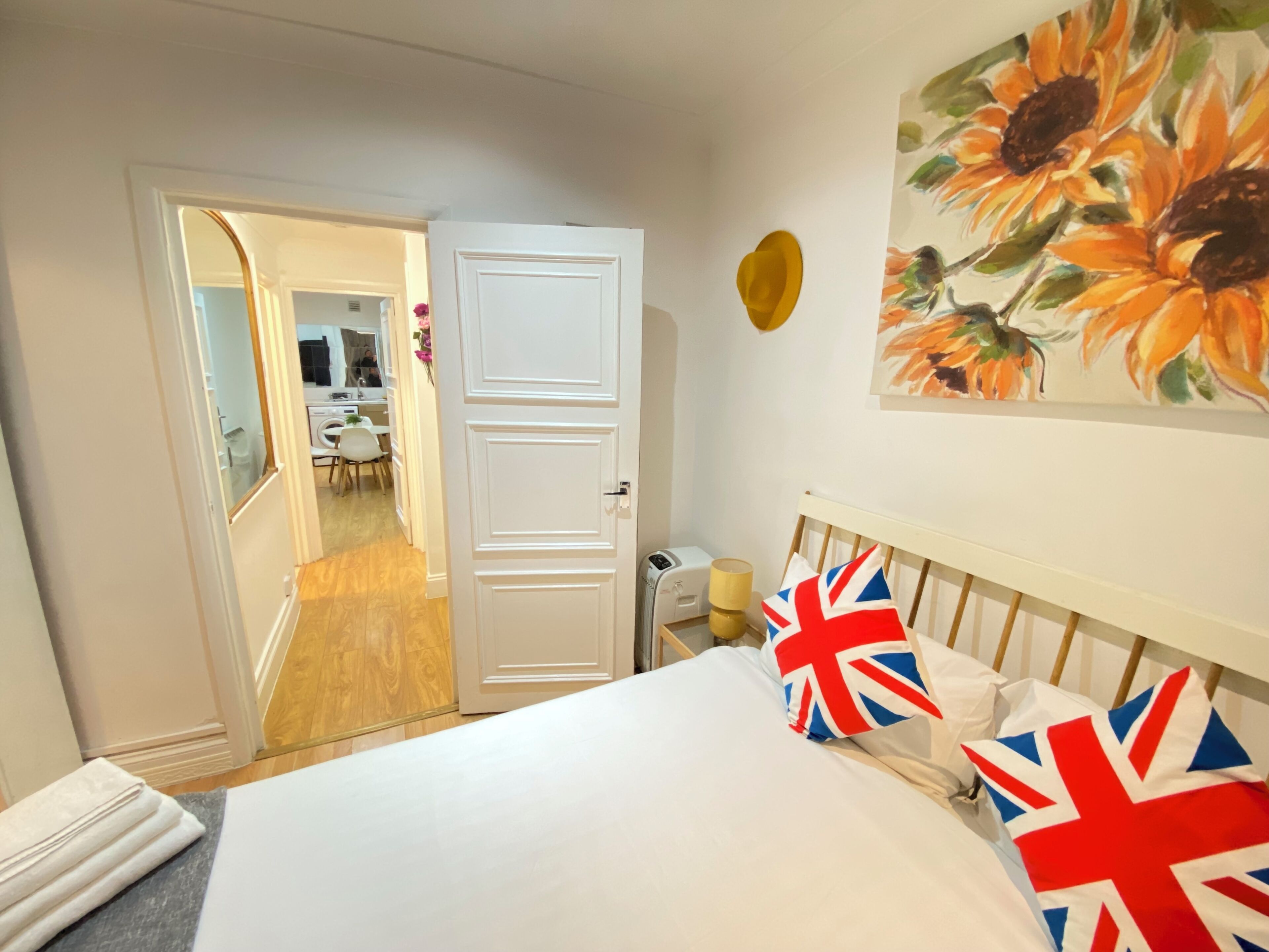 Una habitación de hotel con una cama, un cuadro de girasoles y una puerta que da a un baño.