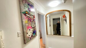 Um corredor com um espelho, uma porta e uma parede com uma pintura abstrata colorida.