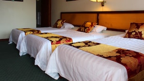 A hotel room with three beds, each with a different patterned bedspread. There is a wall-mounted lamp on the right side of the room. -  Soluxe El Sesteo (San José)