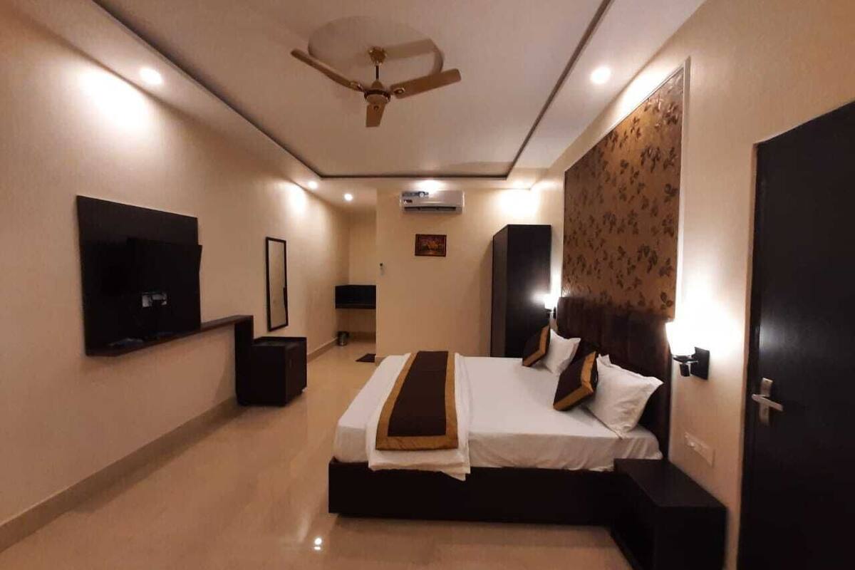 A hotel room with a bed, a ceiling fan, a TV, and a wall-mounted air conditioner.
