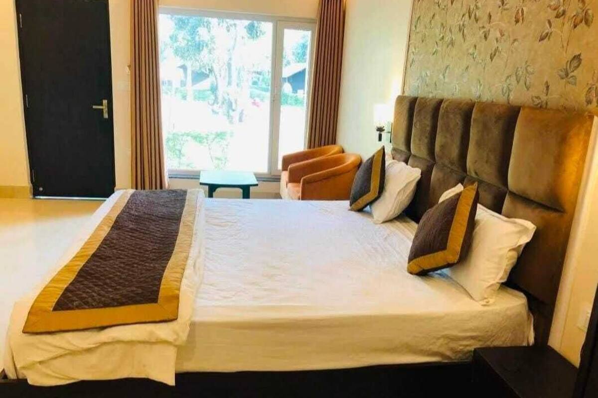 A neatly made bed with a white and brown bedspread, a headboard, and two pillows.
