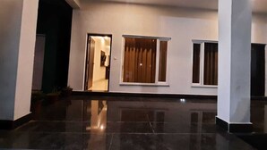 A spacious lobby with a polished floor, large windows, and a door leading to another room. - THE PALMS RESORT (Rishikesh)