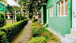 A pathway leading to a green building with steps and a door. - THE PALMS RESORT (Rishikesh)