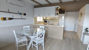 Eine moderne Küche mit weißen Schränken, einem Glastisch und Holzböden.