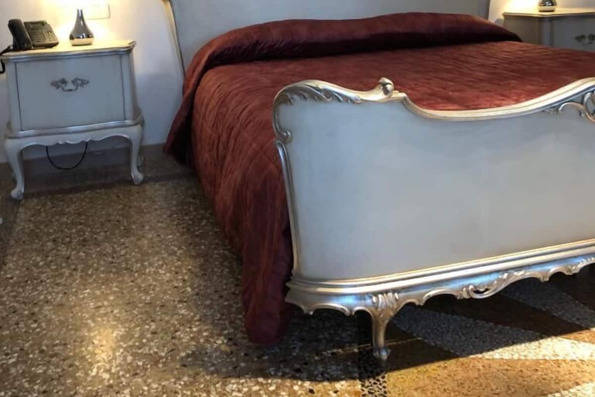 Un dormitorio con una cama, dos mesitas de noche con lámparas y suelo cubierto de alfombra.