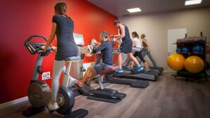Une salle de sport équipée de tapis de course, de vélos d’appartement et de ballons d’exercice.