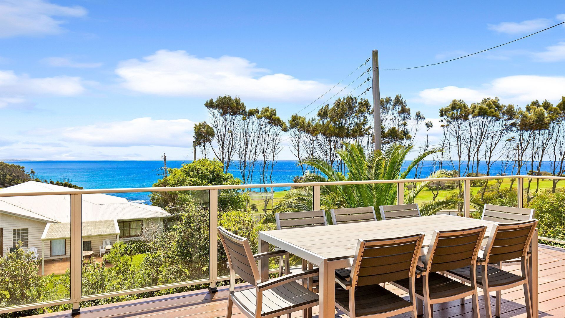 A deck with a table and chairs overlooking a coastal view.